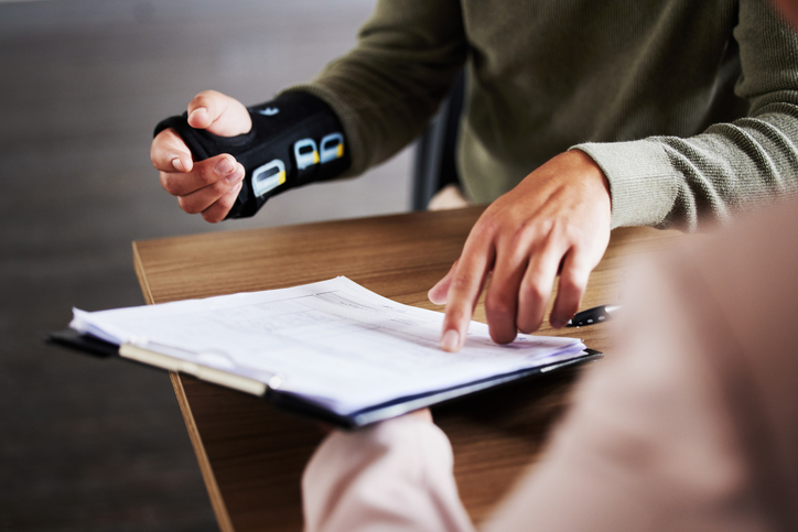 person with injured arm goes over paperwork with another person
