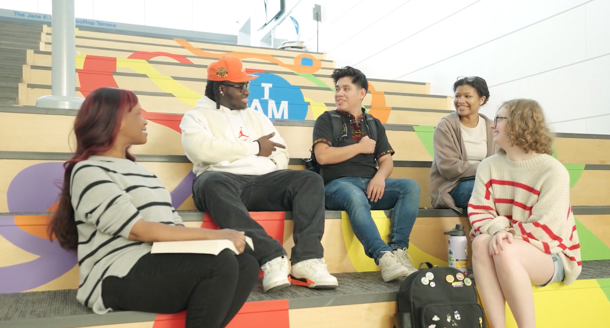 49 Un grupo de estudiantes se sientan juntos en los escalones y conversan.