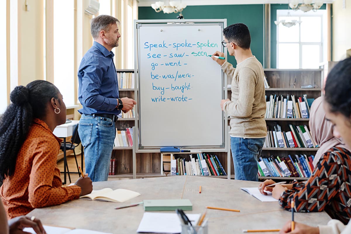 Teacher instructing at white board in front of adult students
