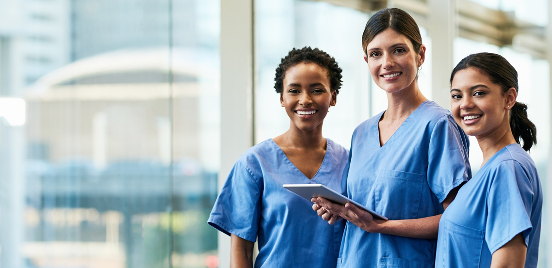 three smiling nurses in front of windows