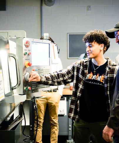 student looks at machine with professor