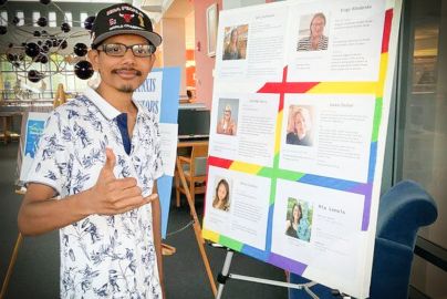 Student gives thumbs up in front of project poster