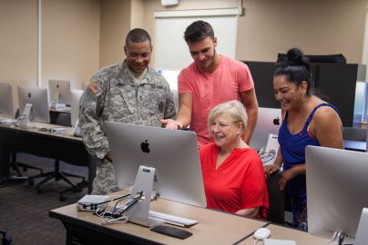 group of students look at large Macbook screen in computer lab